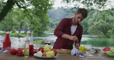 Et hazırlayan ve barbekü için baharat koyan adam ve nehir kenarında akşam yemeği, yaz mutfağında akşam yemeği hazırlayan adam.