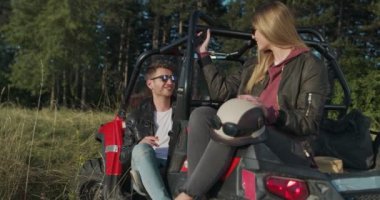 Genç hippi çift sabah off-road arabasında eğleniyor. Hippi kıyafetli bir çift gün doğumunu bekliyor ve eğleniyorlar.