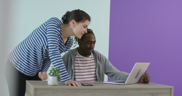 Positiv lächelnder Mann und Frau in der Nähe des Arbeitsplatzes mit Laptop im Büro — Stockvideo