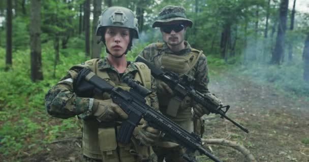 Trupp von Soldaten patrouilliert durch das Waldgebiet, Team mit männlichen und weiblichen Soldaten in dichtem Wald mit Rauch im Hintergrund — Stockvideo