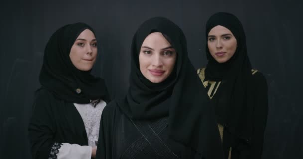 Group portrait of beautiful muslim women in fashionable dress with hijab isolated on black chalkboard background — Stock Video