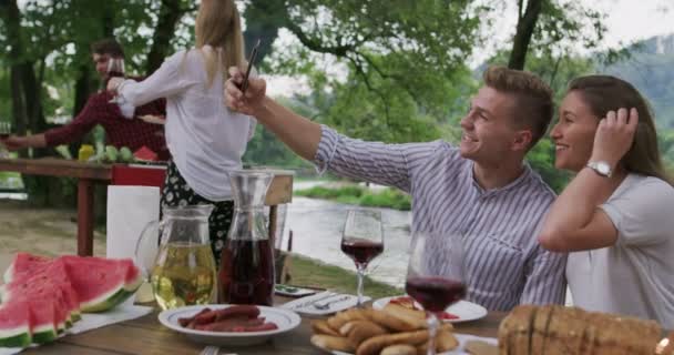 Giovane coppia felice prendendo selfie mentre avendo pic-nic francese cena all'aperto durante le vacanze estive vacanza vicino al fiume a bella natura — Video Stock