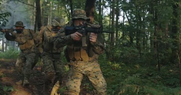 Egy csapat katona, akik tüzelésre kész puskával haladnak át a füstös erdőn, katonai akció közben az erdőn. — Stock videók