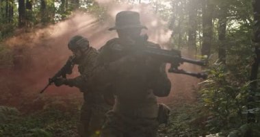 Smokey Ormanı 'ndan tüfekle geçmeye hazır bir grup asker askeri harekat sırasında ormanda koşuyor.