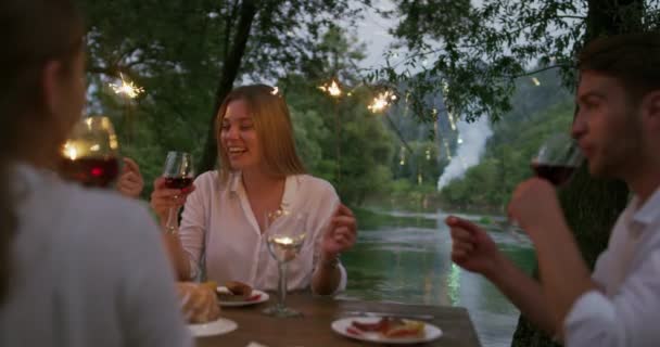 Ungdomsvänskap koncept - Händer rostar rött vinglas bredvid floden på natten — Stockvideo