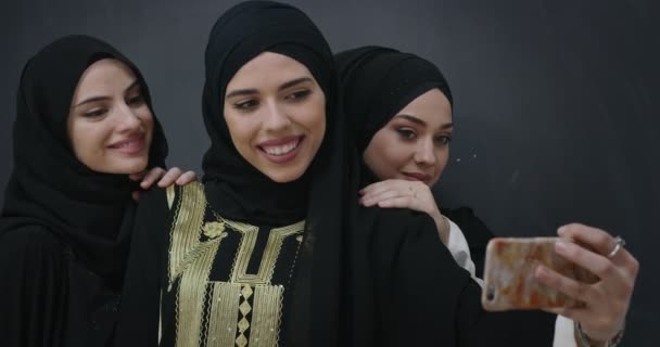 Grupp unga vackra muslimska kvinnor i moderiktig klänning med hijab med mobiltelefon tar selfie — Stockvideo