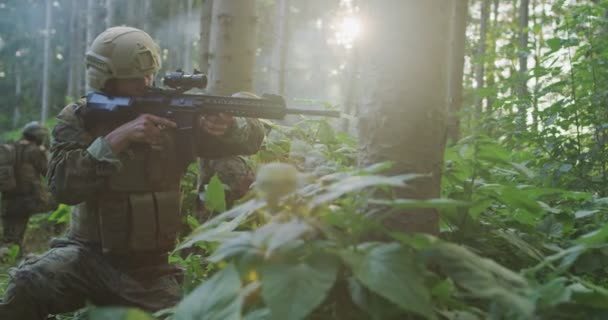 Soldados sosteniendo rifles emboscados en densos frentes durante el día, protegiendo la base con un equipo táctico completo — Vídeos de Stock