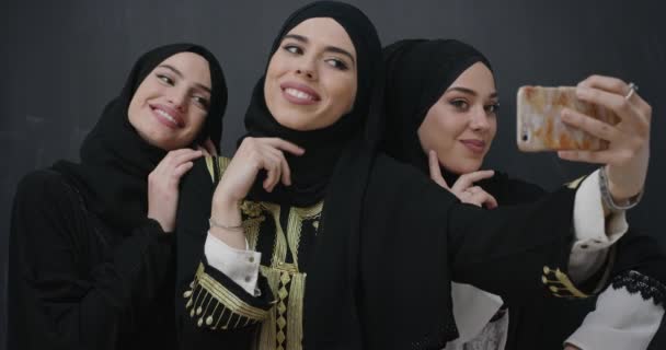 Grupp unga vackra muslimska kvinnor i moderiktig klänning med hijab med mobiltelefon tar selfie — Stockvideo