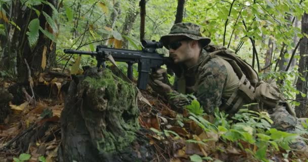 Soldado de fusil totalmente equipado con uniforme de camuflaje que ataca al enemigo, rifle en posición de disparo en bosque denso — Vídeo de stock