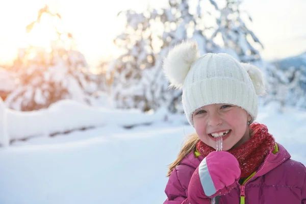 Niedliches kleines Mädchen beim Eiszapfen essen an einem schönen Wintertag — Stockfoto