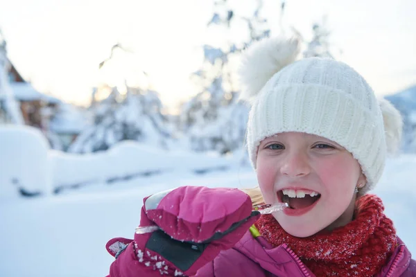 Niedliches kleines Mädchen beim Eiszapfen essen an einem schönen Wintertag — Stockfoto