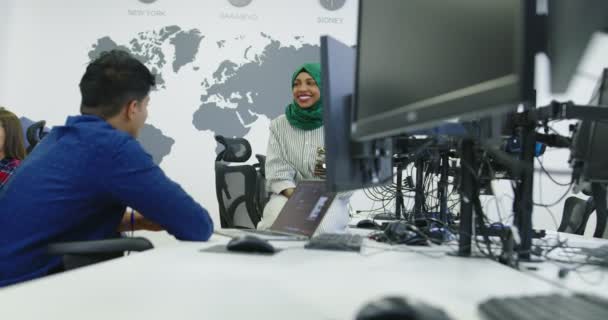 Dos colegas de negocios multiétnicos vestidos casualmente usando una computadora portátil y hablando juntos en la oficina de startups — Vídeos de Stock