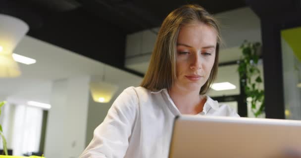 Улыбающаяся стартап-бизнес-леди с помощью планшета, стоя в минималистском офисе — стоковое видео