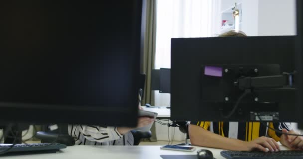 Dos jóvenes colegas de negocios vestidos casualmente usando una computadora y hablando juntos durante el proceso en la oficina de inicio — Vídeos de Stock