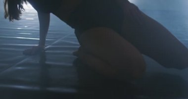 Çağdaş bale dansçısı dumanlı atmosferde pratik yapıyor, dans pratiği sırasında ince esnek bir dans sanatçısı.