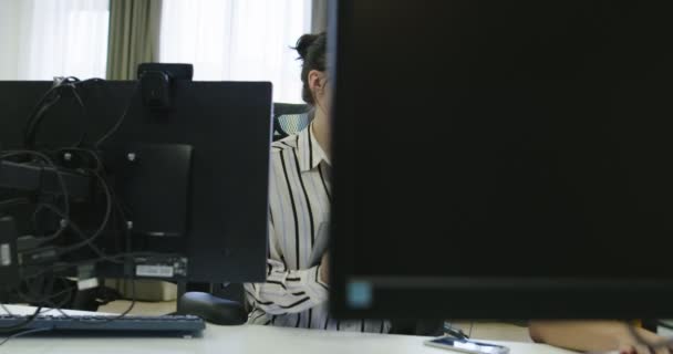 Dois jovens colegas de negócios casualmente vestidos usando um computador e conversando juntos durante o processo no escritório de inicialização — Vídeo de Stock