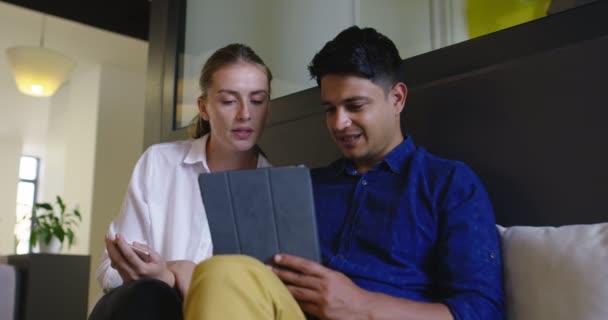 Dos personas atractivas de etnia mixta discutiendo ideas utilizando tableta digital en la oficina de inicio, reunión y planificación de próximos negocios — Vídeos de Stock