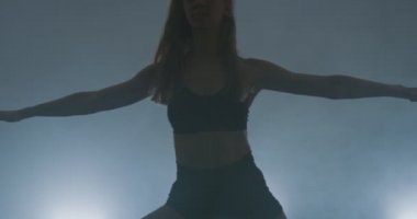 Çağdaş bale dansçısı dumanlı atmosferde pratik yapıyor, dans pratiği sırasında ince esnek bir dans sanatçısı.