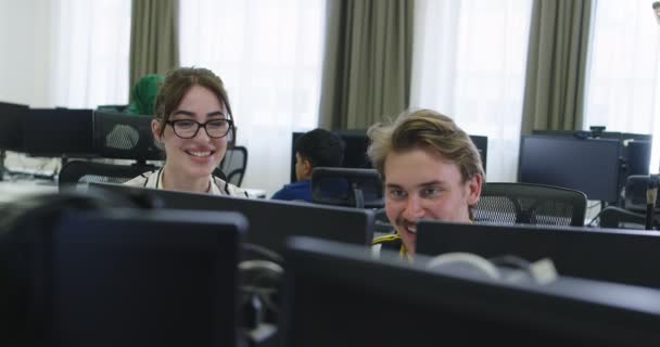 Dois jovens colegas de negócios casualmente vestidos usando um computador e conversando juntos durante o processo no escritório de inicialização — Vídeo de Stock