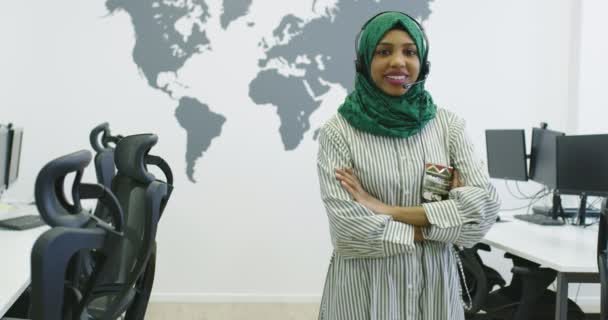 Empresária islâmica feliz com hijab vestindo um fone de ouvido enquanto está no escritório moderno — Vídeo de Stock