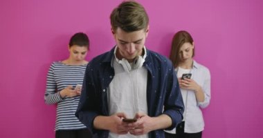 Öğrenciler renkli arka plan üzerinde cep telefonu kullanıyor, eğleniyor ve mesaj gönderiyor. 