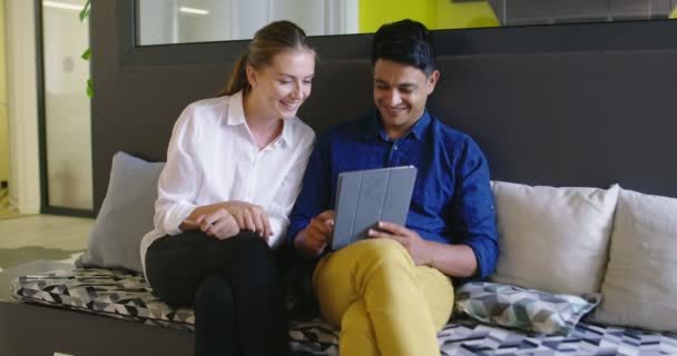 Dos personas atractivas de etnia mixta discutiendo ideas utilizando tableta digital en la oficina de inicio, reunión y planificación de próximos negocios — Vídeos de Stock