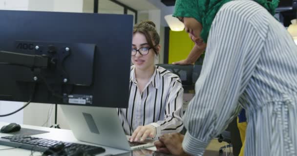 Grupo de jóvenes compañeros de trabajo multiétnicos vestidos casualmente trabajando juntos centrado en el monitor de la computadora en la oficina de inicio — Vídeos de Stock