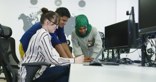 Grupo de jóvenes compañeros de trabajo multiétnicos vestidos casualmente trabajando juntos centrado en el monitor de la computadora en la oficina de inicio — Vídeos de Stock