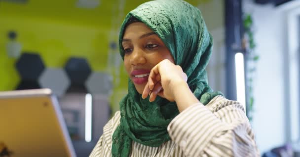 Glad afrikansk muslimsk tjej med hijab som arbetar på en surfplatta i modernt startkontor. — Stockvideo