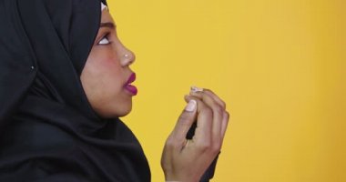 Genç ve güzel Afro-Amerikalı kız izole edilmiş sarı arka planda Müslüman başörtüsü takıyor ve el ele dua ediyor.