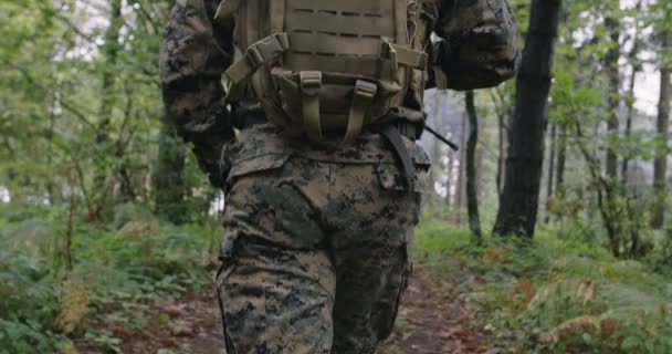 Fullt utrustade soldater bär kamouflageuniform och rör sig genom tät skog under militära insatser — Stockvideo