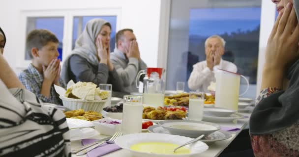 Σύγχρονη πολυεθνική μουσουλμανική οικογένεια προσεύχεται πριν από τη λήψη δείπνο iftar μαζί κατά τη διάρκεια μιας γιορτής ραμαντάν στο σπίτι — Αρχείο Βίντεο