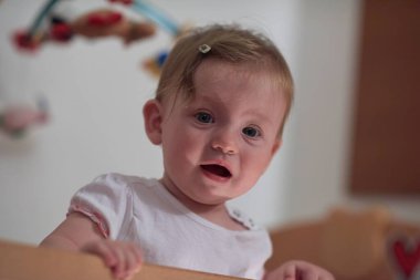 Sevimli küçük bir bebek ve yatakta ilk adımları atıyor.