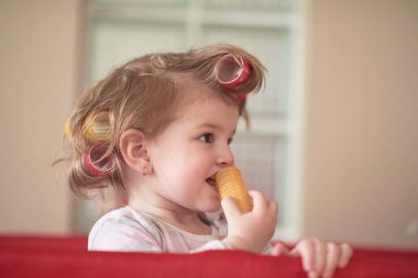 Tuhaf saç stili ve bigudileri olan küçük bir kız bebek.