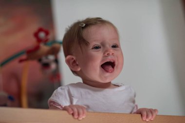 Sevimli küçük bir bebek ve yatakta ilk adımları atıyor.