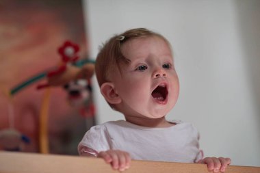 Sevimli küçük bir bebek ve yatakta ilk adımları atıyor.