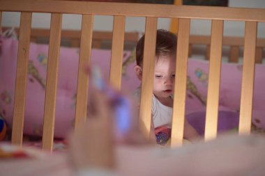 Sevimli küçük bir bebek ve yatakta ilk adımları atıyor.