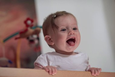 Sevimli küçük bir bebek ve yatakta ilk adımları atıyor.