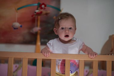 Sevimli küçük bir bebek ve yatakta ilk adımları atıyor.