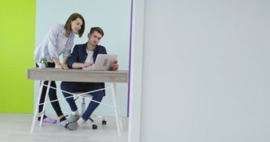 İş yerinin yakınında laptopla iş birliği yapan gülümseyen bir adam ve kadın.
