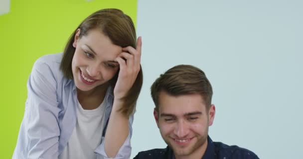 Θετικός χαμογελαστός άνδρας και γυναίκα κοντά στον χώρο εργασίας με φορητό υπολογιστή που συνεργάζεται στο γραφείο — Αρχείο Βίντεο