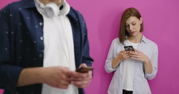 Conceito ciumento, namorado usando telefone enquanto sua namorada mensagens de texto no telefone isolado em fundo de cor — Vídeo de Stock