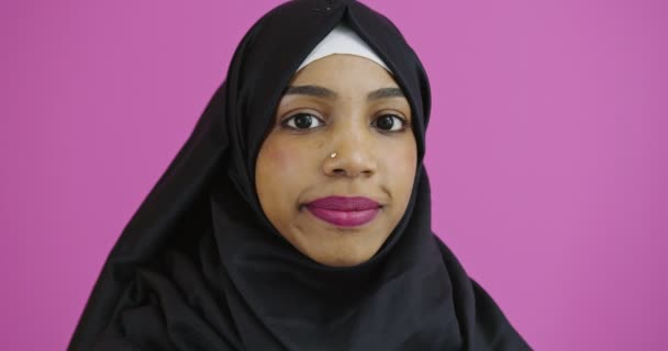 若いです美しいですアフリカ系アメリカ人の女の子身に着けていますムスリムヒジャーブ以上カラフルな背景笑顔と笑い,正のイスラム教徒の女性 — ストック動画