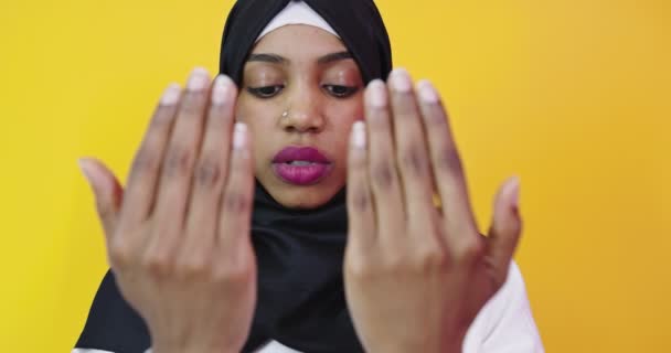 Jeune belle fille afro-américaine portant hijab musulman sur fond jaune isolé priant avec les mains ensemble — Video