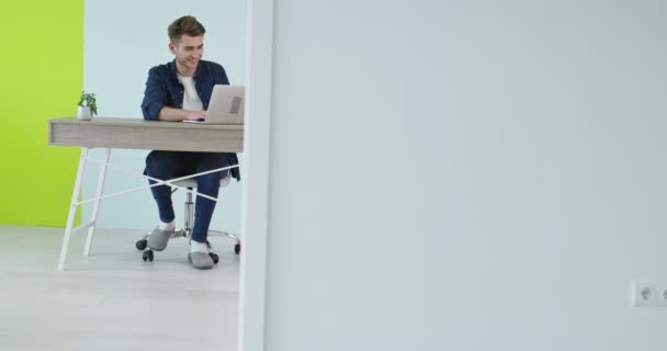 Joven guapo usando un portátil en una oficina moderna, freelancer trabajando en casa nuevo proyecto — Vídeos de Stock