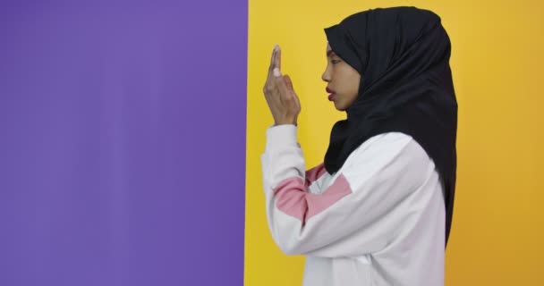 Νεαρή όμορφη Αφρο-Αμερικανίδα που φοράει μουσουλμανική μαντίλα πάνω από το χρώμα φόντο προσεύχεται με τα χέρια μαζί ζητώντας συγχώρεση — Αρχείο Βίντεο