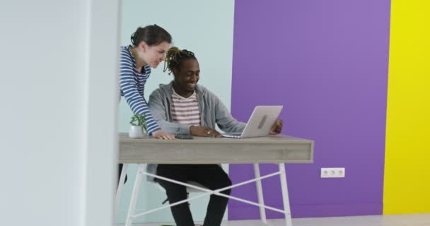Pria dan wanita tersenyum positif di dekat tempat kerja dengan laptop yang bekerja sama di kantor — Stok Video