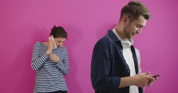 Conceito ciumento, namorado usando telefone enquanto sua namorada mensagens de texto no telefone isolado em fundo de cor — Vídeo de Stock