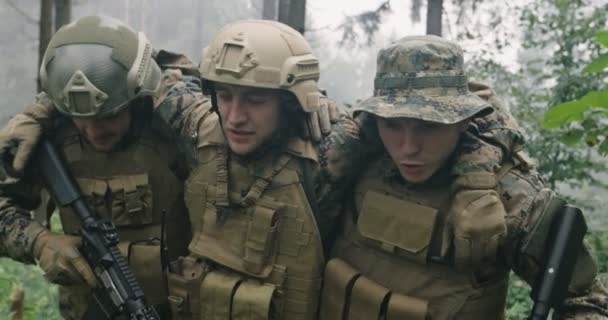 Medic troops saving soldier in dense forest during military action, squad saving soldier who is bleeding, evacuation action — Stock Video