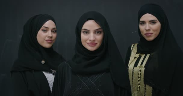 Group portrait of beautiful muslim women in fashionable dress with hijab isolated on black chalkboard background — Stock Video